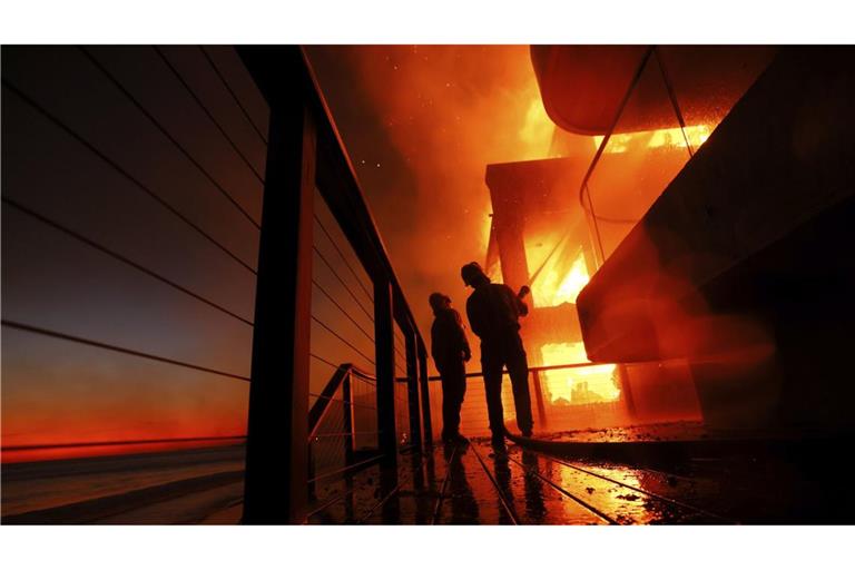 Am Strand von Malibu versuchen Feuerwehrleute ein brennendes Haus zu löschen.