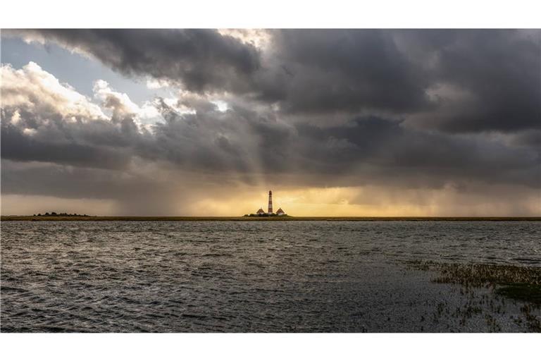 An den Küsten steigt die Flut: Leuchtturm Westheversand auf einer Warft der Halbinsel Eiderstedt.