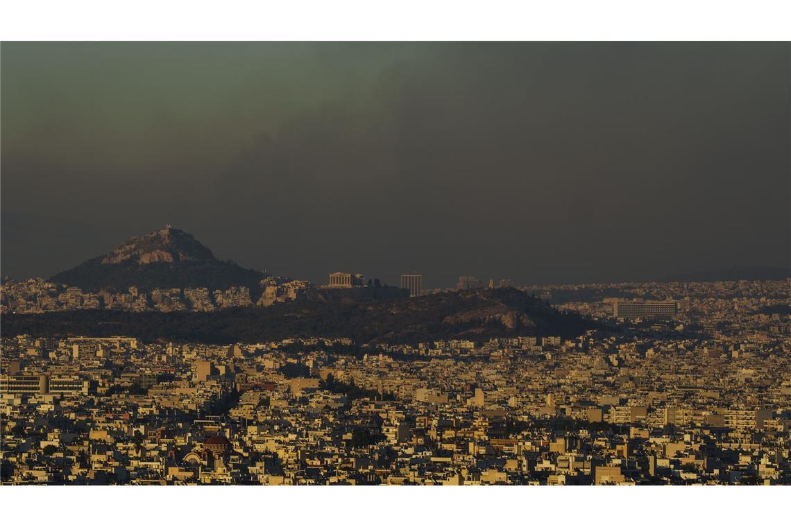 Athen bei Tag am 12. August 2024: Eine Gesamtansicht der griechischen Hauptstadt  dem Akropolis-Hügel (Mi.), während ein Feuer im nördlichen Teil der Stadt brennt.