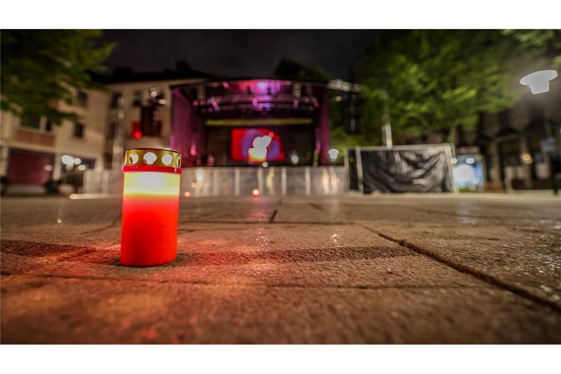 Auf dem Fronhof in Solingen stehen am Abend vor einer Bühne drei einzelne Kerzen für die drei getöteten Menschen der Messerattacke auf dem Stadtfest.