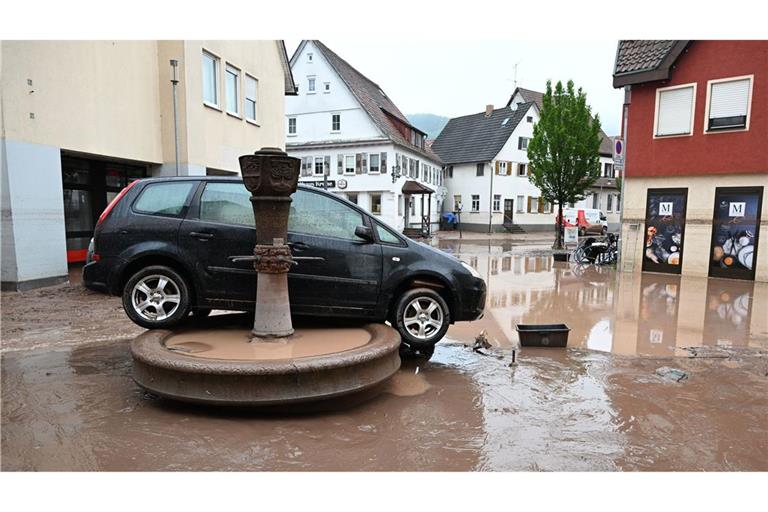 Auf einem Brunnen in Rudersberg (Rems-Murr-Kreis) steht Anfang Juni 2024 ein durch Hochwasser weggespültes Auto.