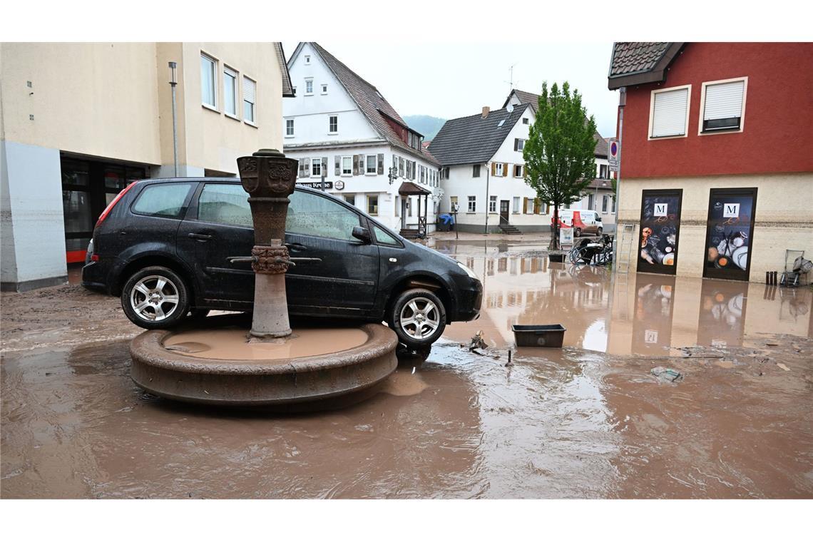 Auf einem Brunnen in Rudersberg steht ein durch ein Hochwasser weggespültes Auto.