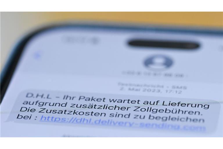 Auf einem Smartphone ist eine Betrugs-SMS zu lesen, in der Kriminelle ein Paket ankündigen und dafür Zollgebühren einfordern.