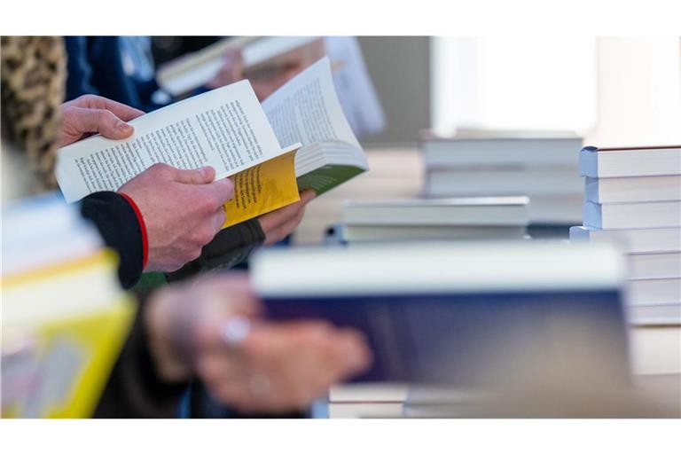 Besucher der Leipziger Buchmesse lesen im März 2024 am Stand eines Verlages.