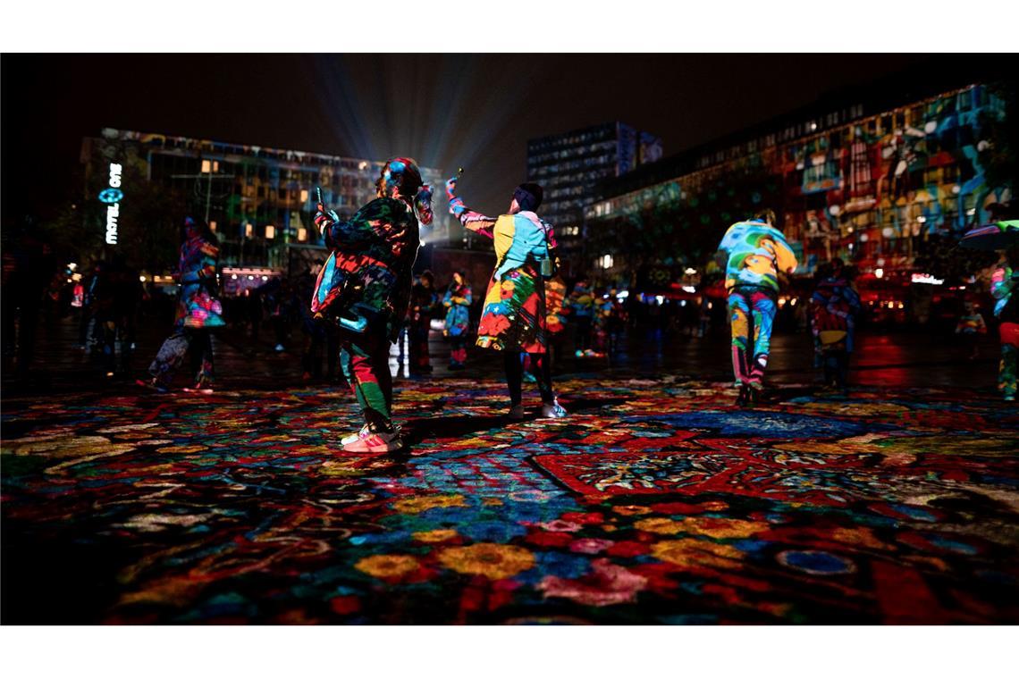 Besucher laufen durch die Projektion der „Big Picture“ des Künstler Daniel Margraf auf dem Kennedy-Platz beim „Essen Light Festival“