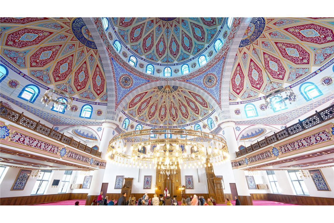 Besucher sitzen am Tag der offenen Moschee bei einer Führung im prächtigen Innenraum in der DITIB-Merkez Moschee in Duisburg auf dem Teppich im Gebetsraum.