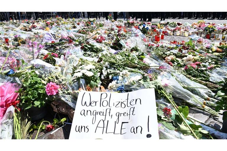 Blumen und Kerzen liegen auf dem Marktplatz in Mannheim zur Erinnerung an einen getöteten Polizisten.