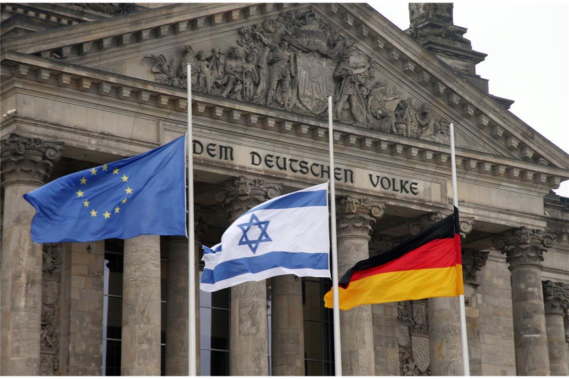 Die europäische, die israelische und die deutsche Flagge auf halbmast vor dem Reichstag in Berlin.