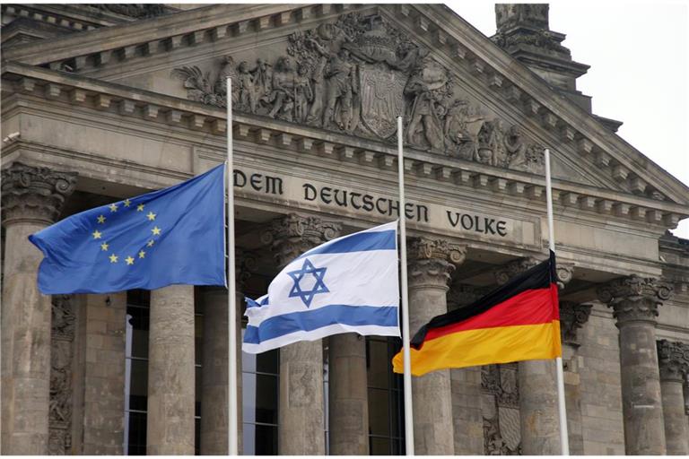 Die europäische, die israelische und die deutsche Flagge auf halbmast vor dem Reichstag in Berlin.