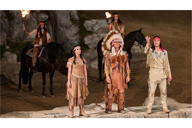 Die Schauspieler Sila Sahin als Ribanna (v. li. n. re.), Sascha Hödl als Enyeto und Alexander Klaws als Winnetou sowie weitere Darsteller stehen während der Premiere von „Winnetou II - Ribanna und Old Firehand“. am 29. Juni 2024  auf der Bühne der Karl-May-Spiele im Freilichttheater am Kalkberg.