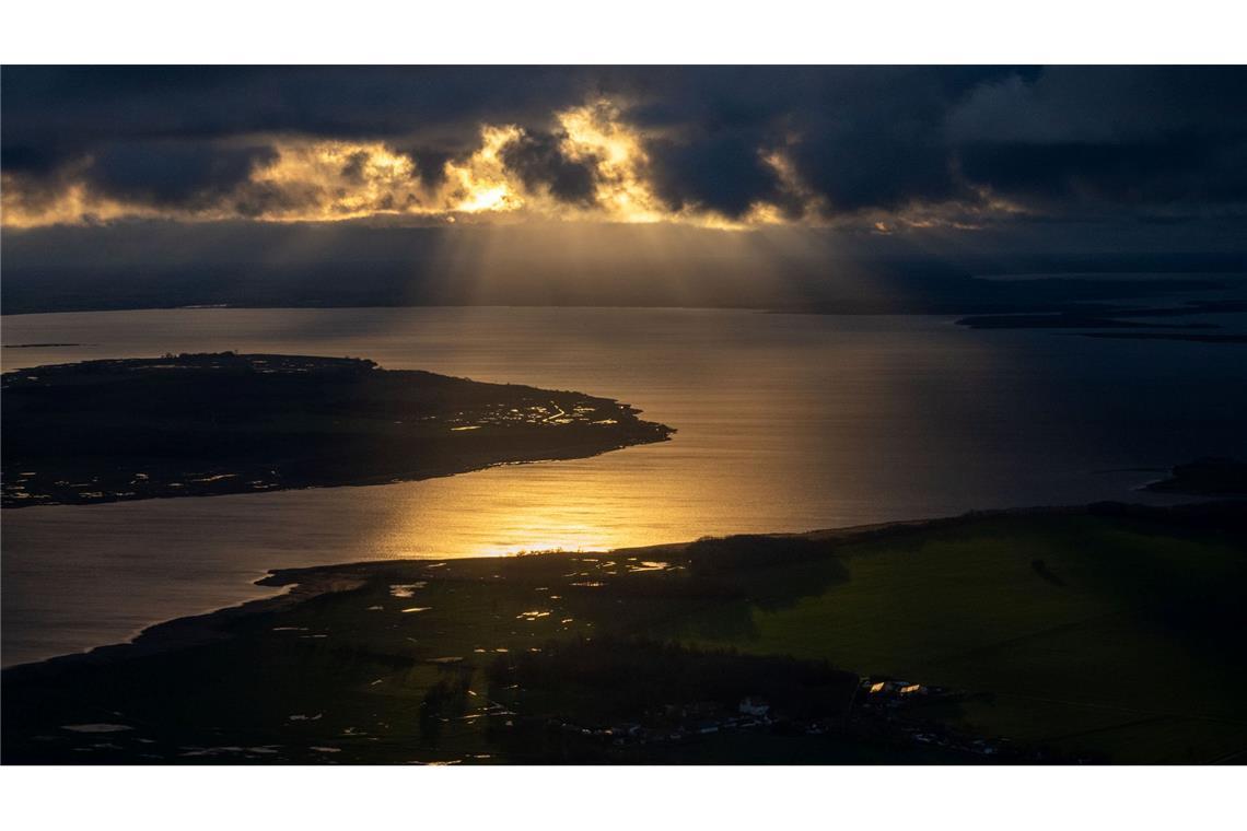 Die Sonne geht hinter Wolken über der Insel Rügen unter.