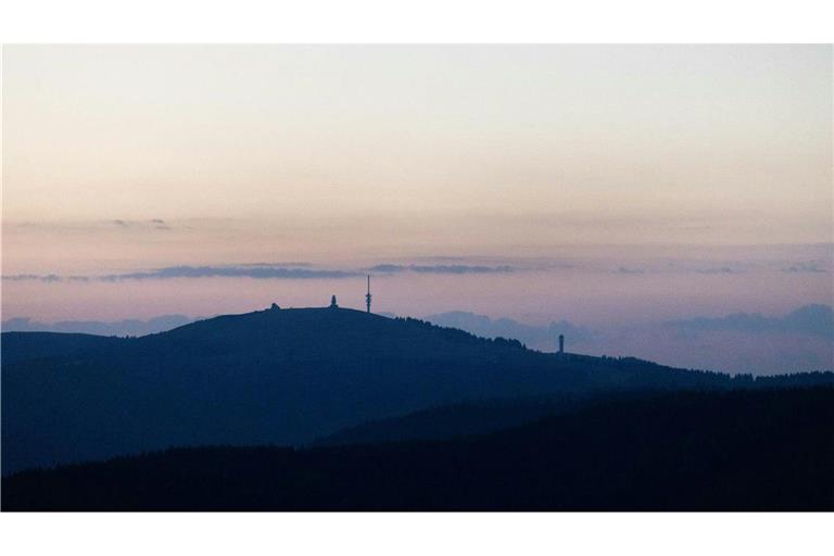 Die Umrisse des Feldbergs und der darauf stehenden Gebäude zeichnen sich bei Oberried vor dem Morgenhimmel ab.