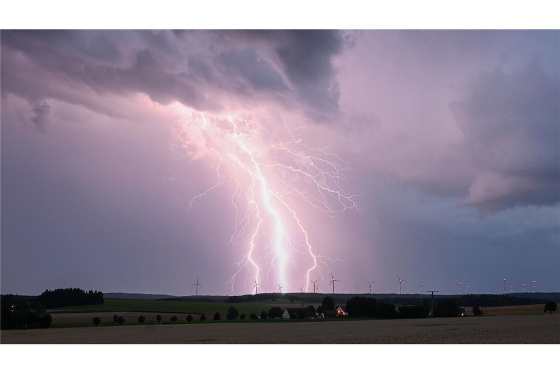 Ein Blitz zuckt bei einem Sommergewitter am abendlichen Himmel über Bartholomä auf der Schwäbischen Alb.