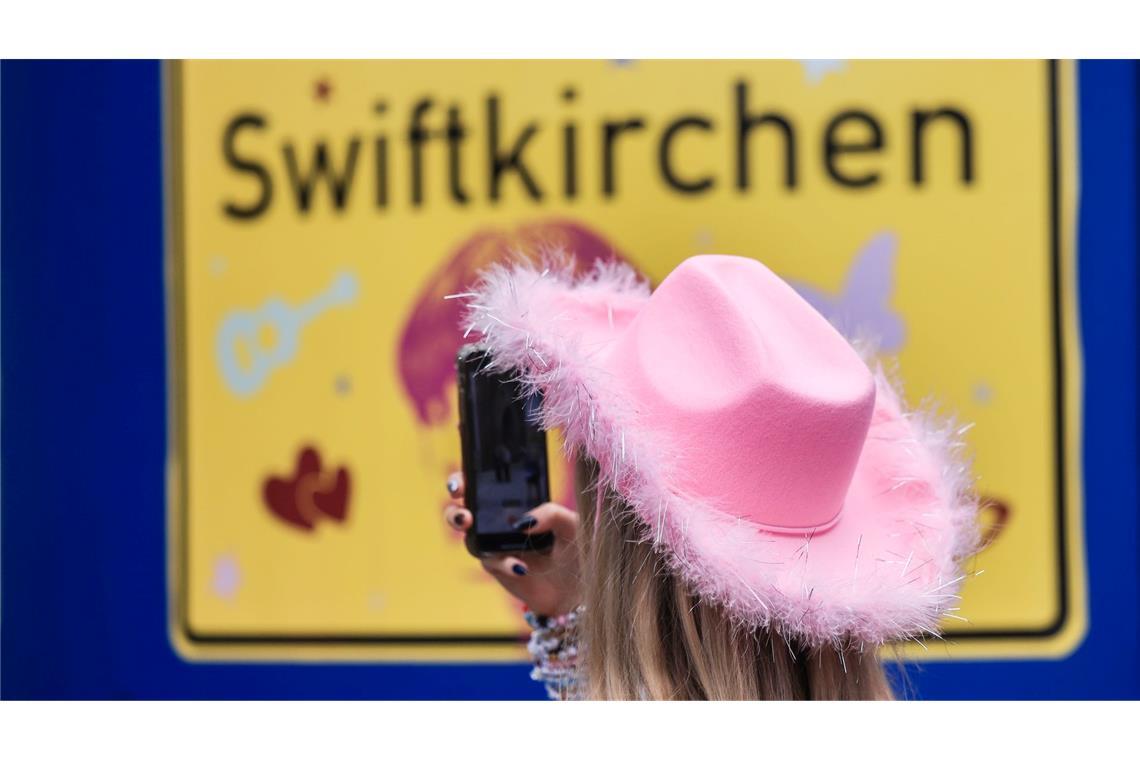 Ein Fan fotografiert vor dem Konzert der Sängerin Taylor Swift in Gelsenkirchen ein "Swiftkirchen"-Schild. Während des Konzerts am Abend zog der Datenverbrauch in den Handynetzen in der Veltins Arena kräftig an.