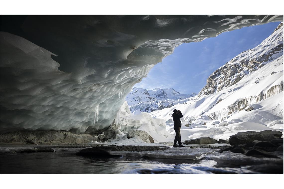 Ein Fotograf macht ein Bild in einer Gletscherhöhle am Morteratschgletscher. Der Morteratschgletscher ist ein Alpen-Gletscher m Kanton Graubünden.