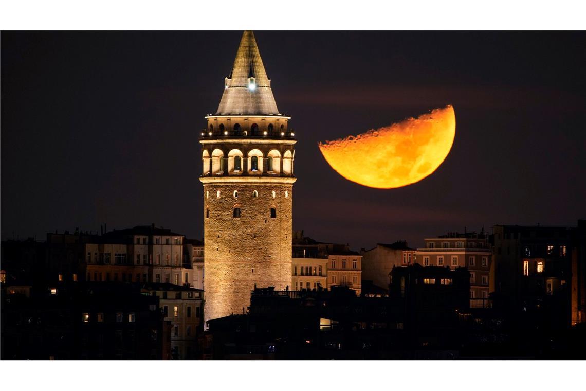 Ein Halbmond geht neben dem Galata-Turm in Istanbul unter.