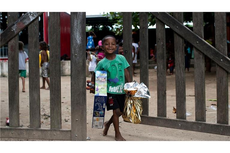 Ein Kind trägt Weihnachtsspenden der sozialen Bewegung SOMOS in der Favela Jardim Gramacho in Brasilien.