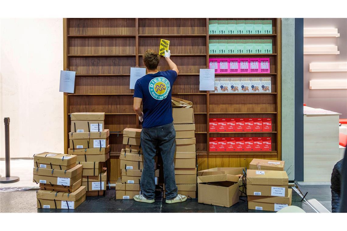 Ein Mann räumt am Stand von S. Fischer Verlage die Ausstellungsregale mit Büchern ein.