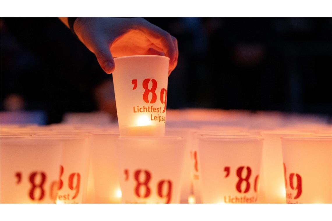 Ein Mann stellt auf dem Augustusplatz eine Kerze mit der Aufschrift "'89 - Lichtfest Leipzig" auf.