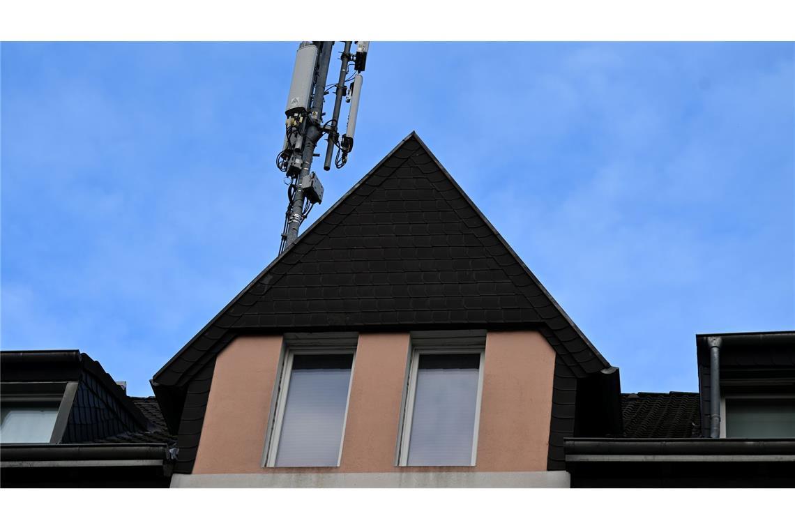 Ein Mobilfunk-Mast mit Antennen im Funkstandard 5G (quadratisch) und 4G (länglich) ist auf dem Dach eines Wohnhauses montiert.