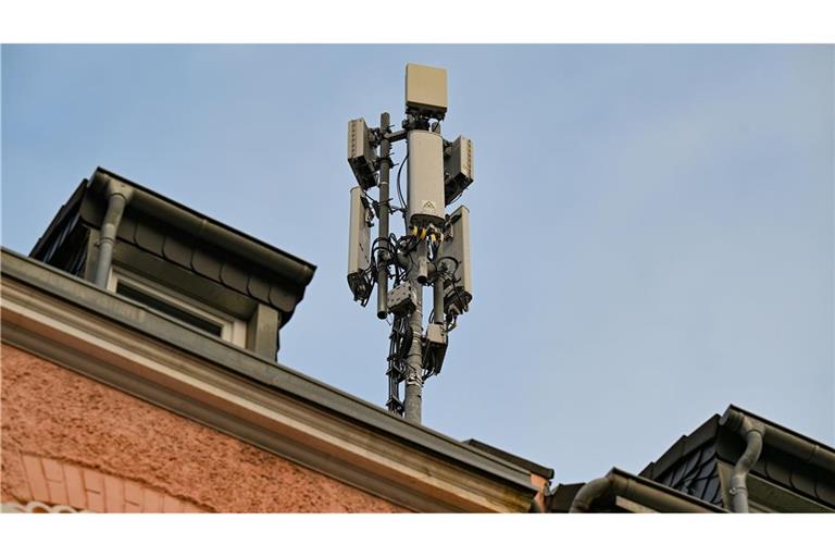 Ein Mobilfunkmast mit 4G/LTE-Antennen (länglich) und 5G-Antennen (quadratisch) steht auf einem Dach eines Wohnhauses.