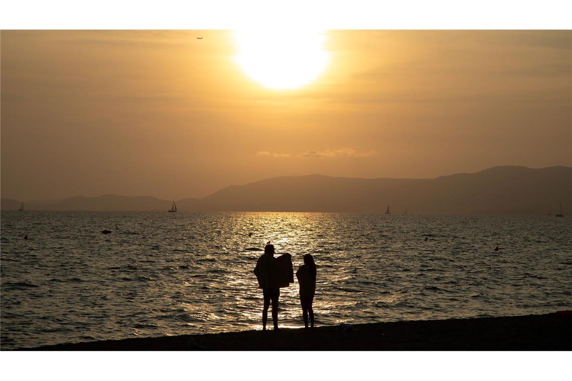 Ein Paar beobachtet den Sonnenuntergang am Strand von Arenal auf Mallorca.