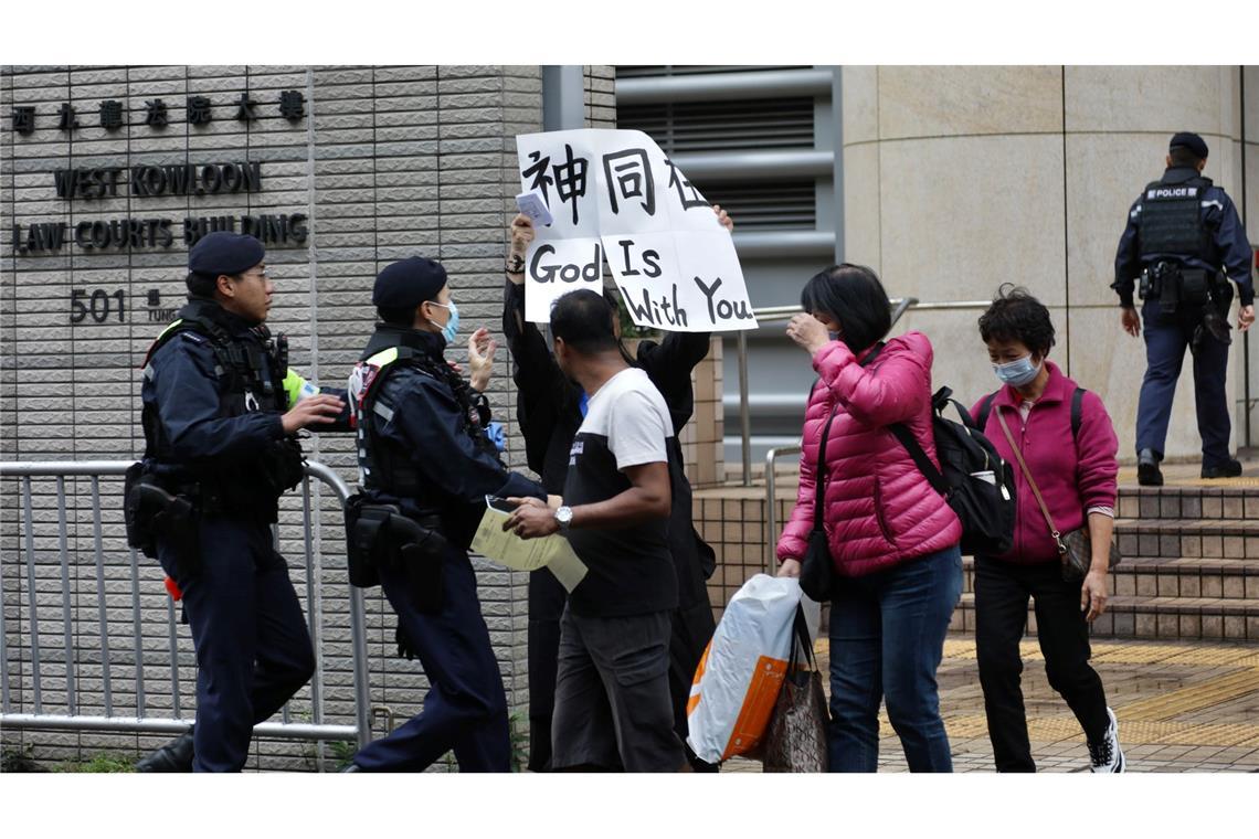 Ein Polizist versucht, eine Frau daran zu hindern, vor dem Gericht in West Kowloon ein Transparent mit der Aufschrift "Gott ist mit dir" in englischer und chinesischer Sprache zu zeigen. Ein Gericht in Hongkong hat 45 Demokratie-Aktivisten zu Haftstrafen von bis zu zehn Jahren verurteilt.