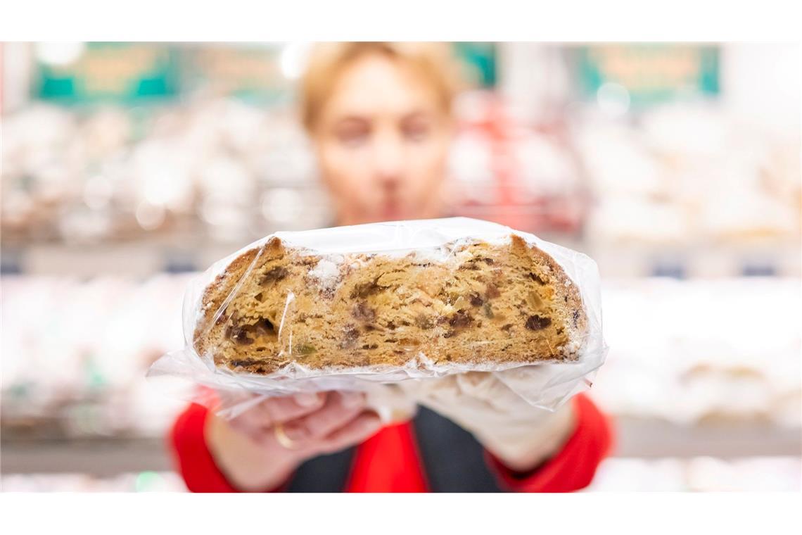 Ein Verkäuferin präsentiert auf dem Erfurter Weihnachtsmarkt einen Stollen.