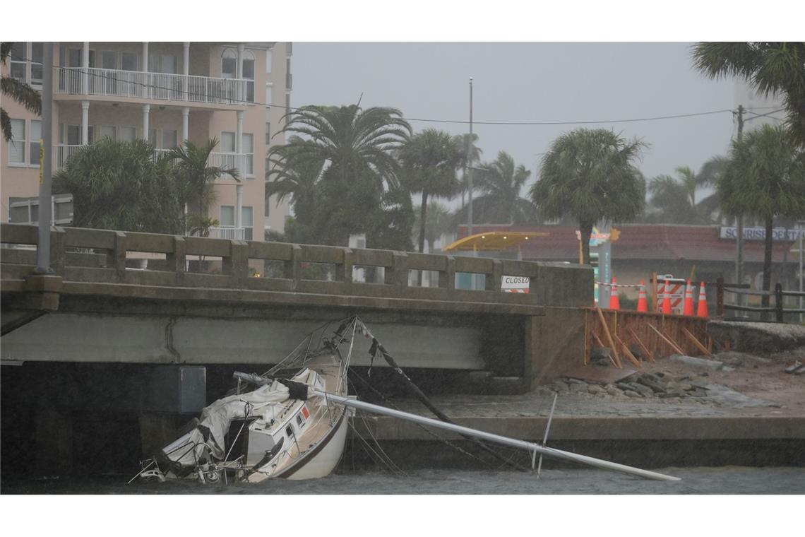 Ein von Hurrikan "Helene" beschädigtes Boot liegt unter einer Brücke, während sich "Milton" nähert.