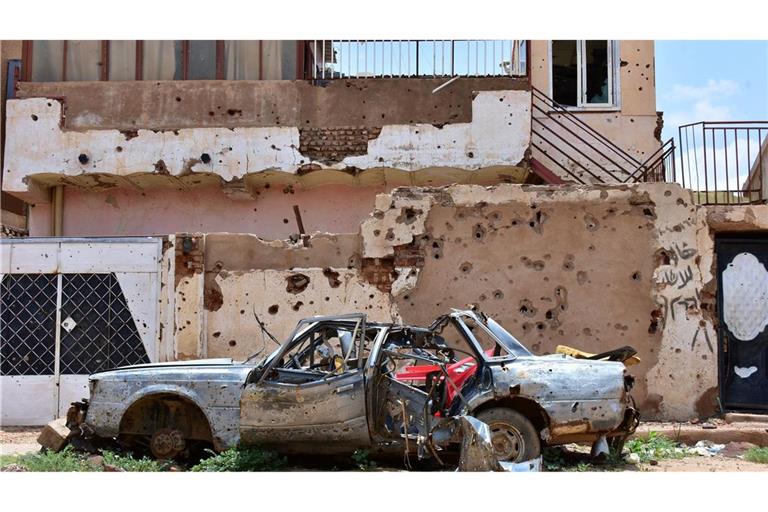 Ein zerstörtes Auto steht im sudanesischen Omdurman vor einem Haus voller Einschüsse. (Archivbild)