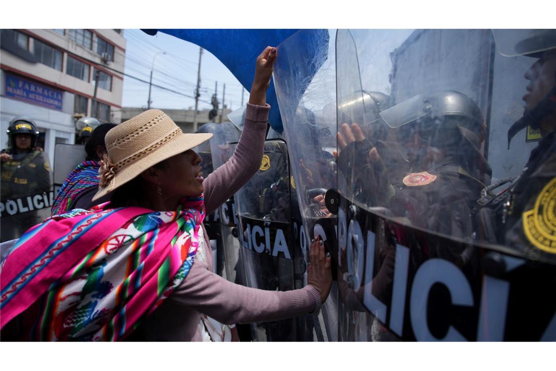 Eine Frau, die in Peru gegen die Regierung protestiert, drückt gegen Schutzschilder von Polizisten, die den Gipfel der Asiatisch-Pazifischen Wirtschaftsgemeinschaft (APEC) schützen.