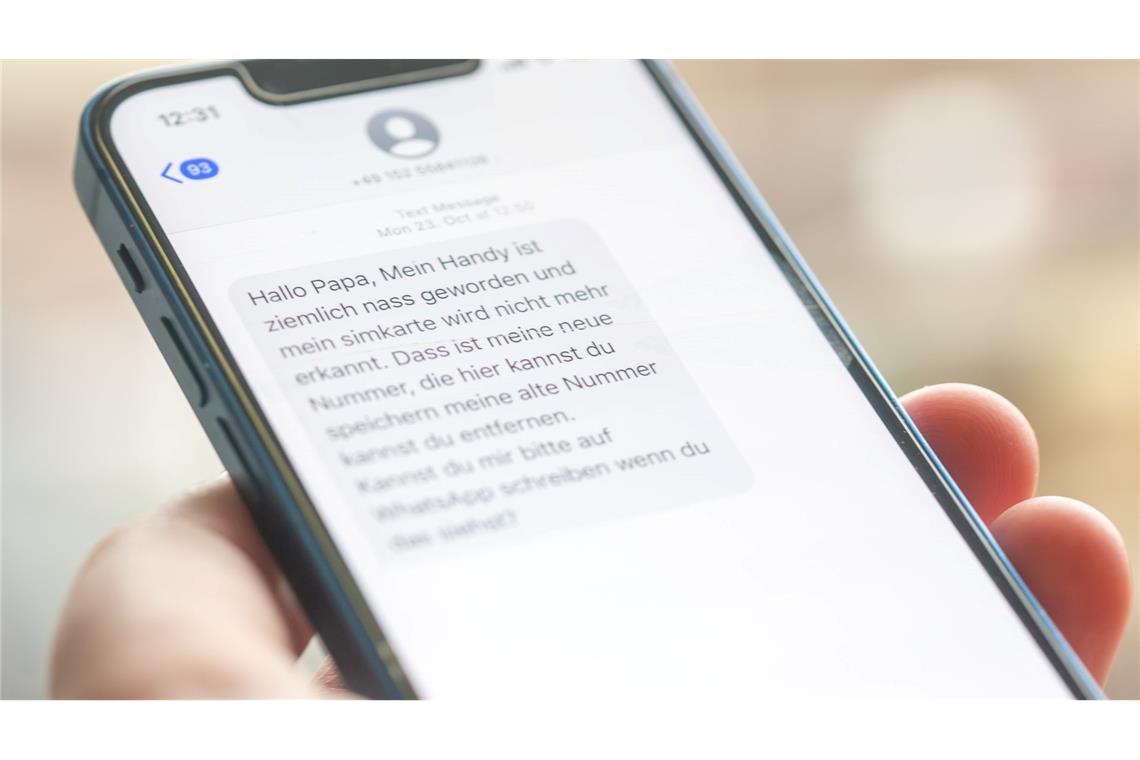Eine Frau hält ein Smartphone in ihrer Hand, auf dessen Display eine Betrugs-SMS zu lesen ist.