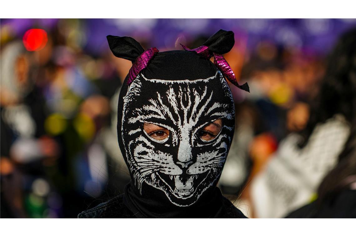 Eine Frau mit einer Maske tritt während eines Marsches anlässlich des Internationalen Tages zur Beseitigung von Gewalt gegen Frauen in Santiago in Chile auf.