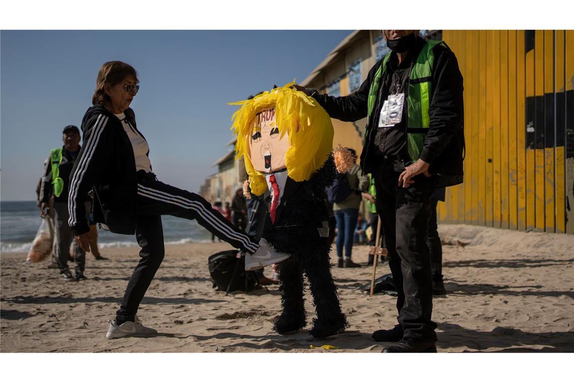 Eine mexikanische Frau tritt eine Piñata von Donald Trump.