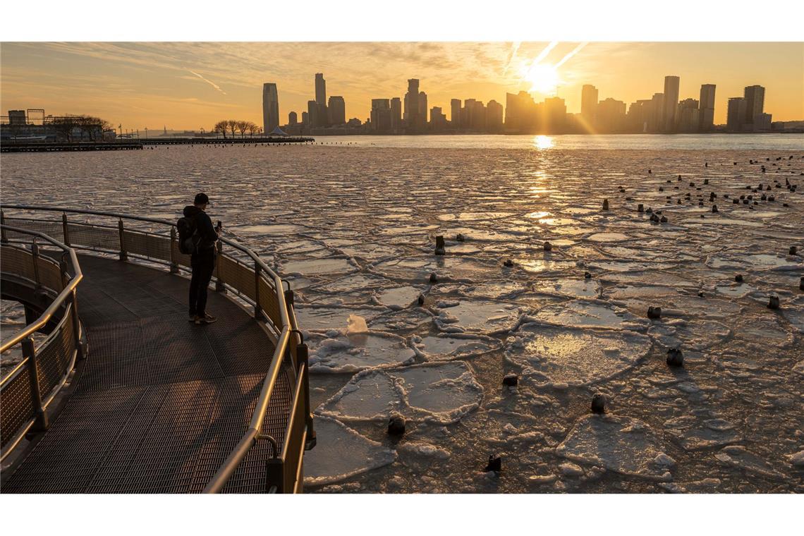 Eine Person macht ein Foto vom eisbedeckten Hudson River in New York.