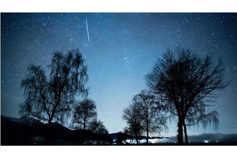 Eine Sternschnuppe ist während des Geminiden-Meteorenstroms im bayerischen Kochel am See zu sehen.