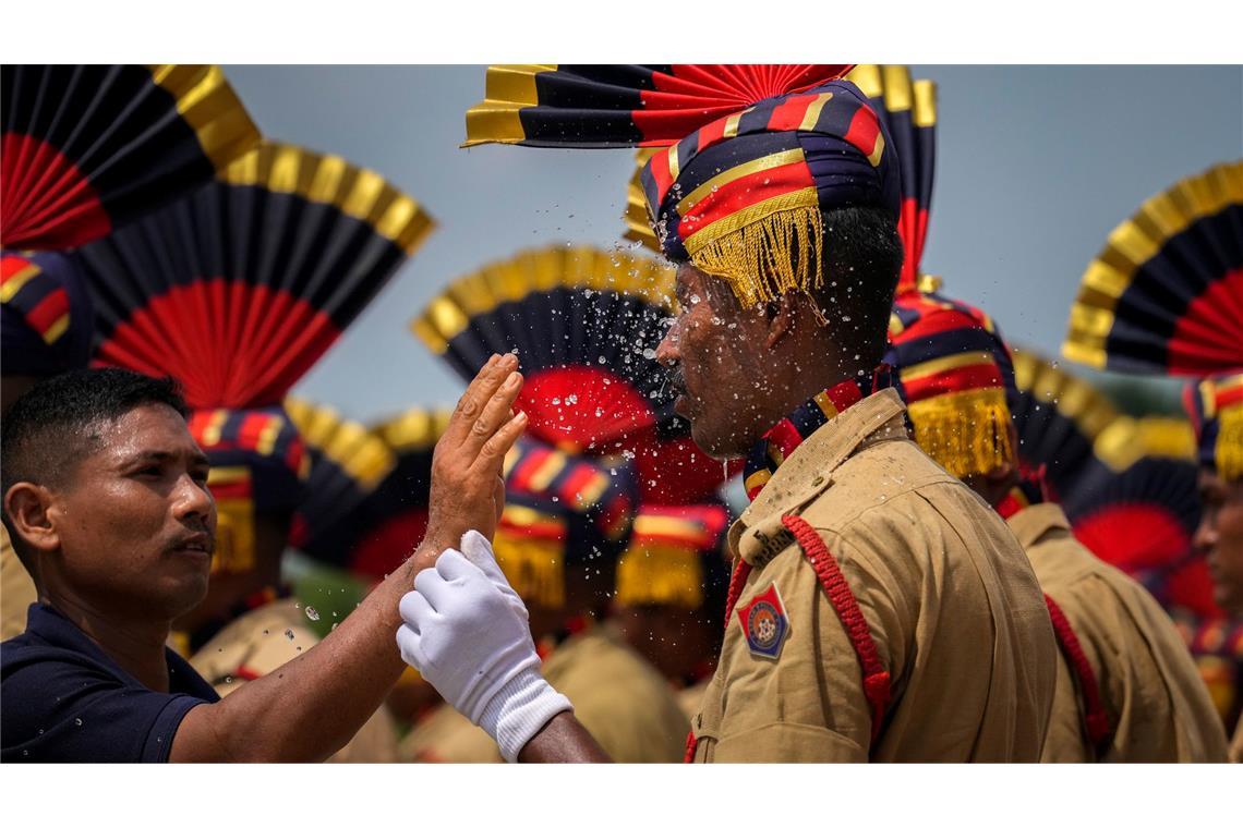 Erfrischung bei Parade in Indien: Ein Zivilschützer bespritzt ein Mitglied der Assam-Polizei mit Wasser, während sie an einem heißen sonnigen Tag an einer Parade zum Unabhängigkeitstag teilnehmen.