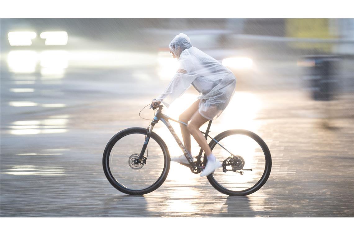 Fahrradfahren im Sommerregen: Ein Fahrradfahrer fährt am frühen Morgen durch die Erfurter Innenstadt.