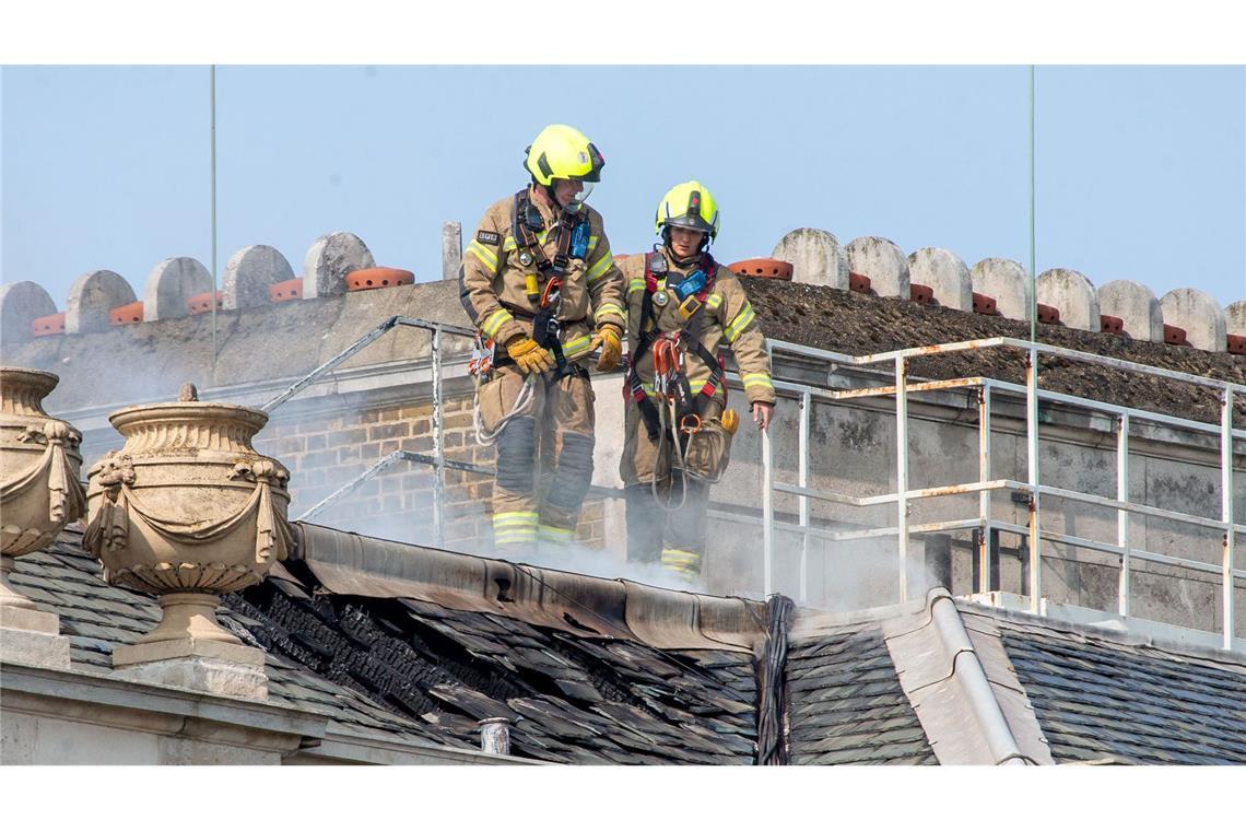 Feuerwehrleute kämpfen gegen Flammen am Dach.