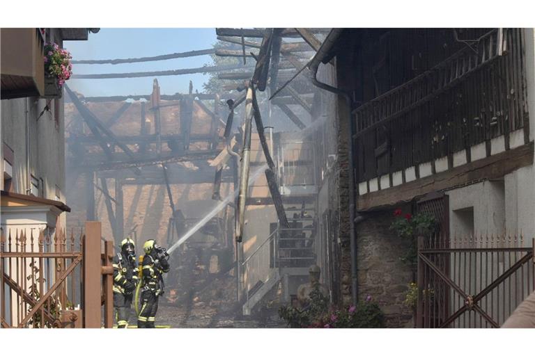 Feuerwehrleute löschen den Brand in einer Scheune in einem eng bebauten Wohngebiet im Landkreis Karlsruhe.