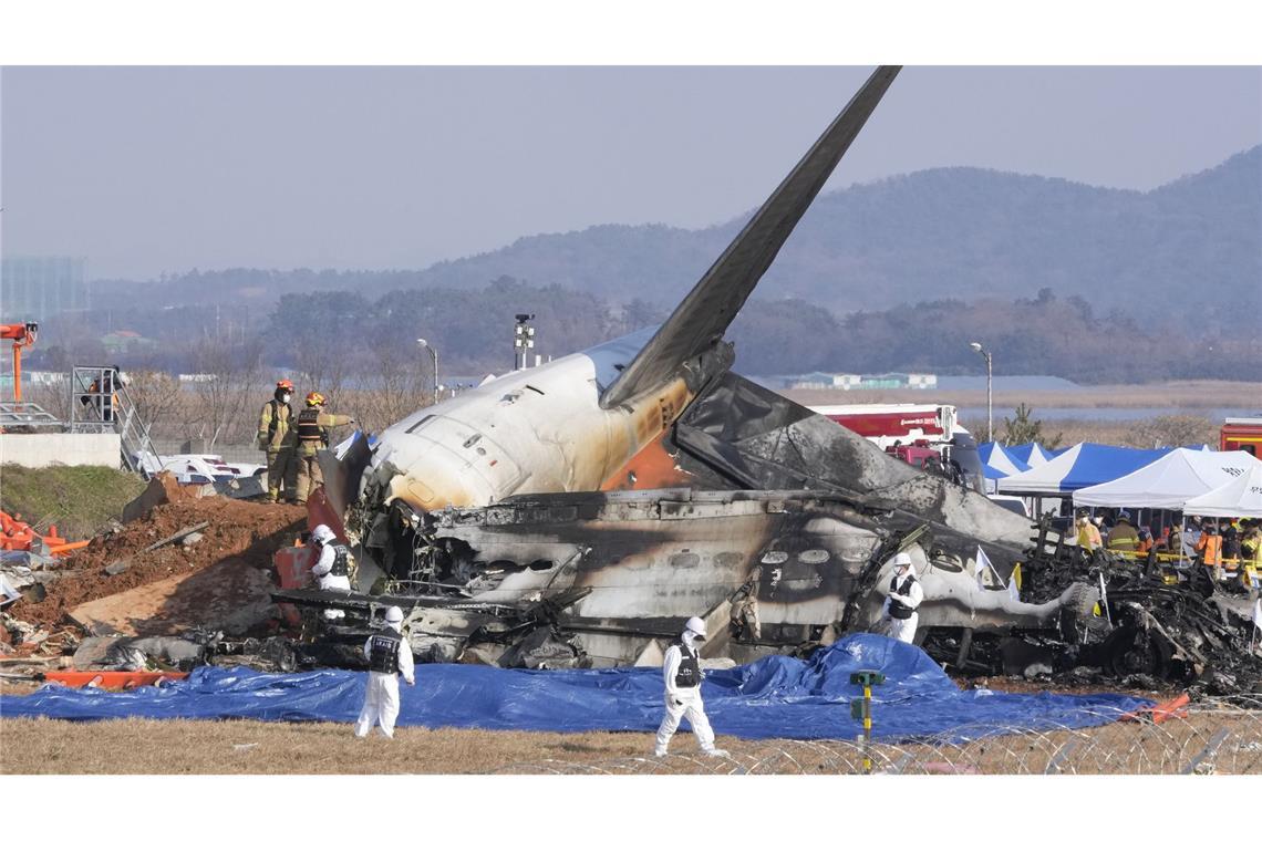 Feuerwehrleute und Rettungskräfte arbeiten in der Nähe des Wracks eines Passagierflugzeugs am internationalen Flughafen von Muan.