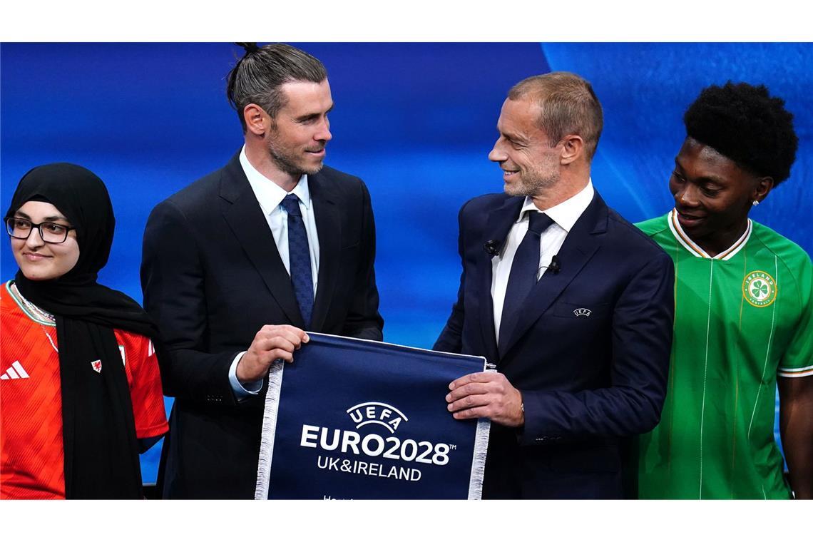 Gareth Bale (M,l.), Delegierter aus Wales, und Aleksander Ceferin, Präsident der UEFA, halten einen UEFA-Euro-2028-Wimpel während der Bekanntgabe der Euro-2028-Gastgeber.