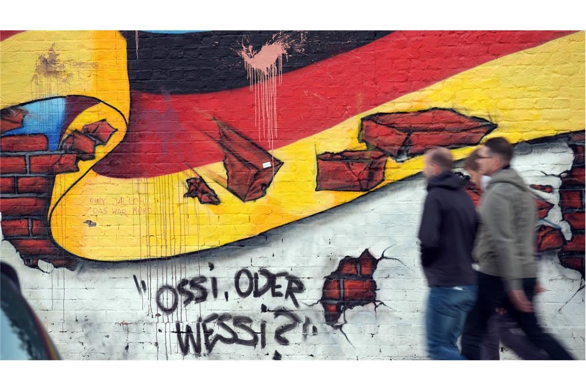 Graffito in Berlin: Auch 35 Jahre nach der Wende wird über die Ost und West diskutiert.