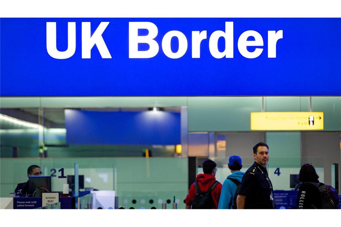 Grenzbeamte stehen am Flughafen Heathrow unter einem Schild mit der Aufschrift „UK Border“. Reisen in das Königreich werden künftig etwas komplizierter.