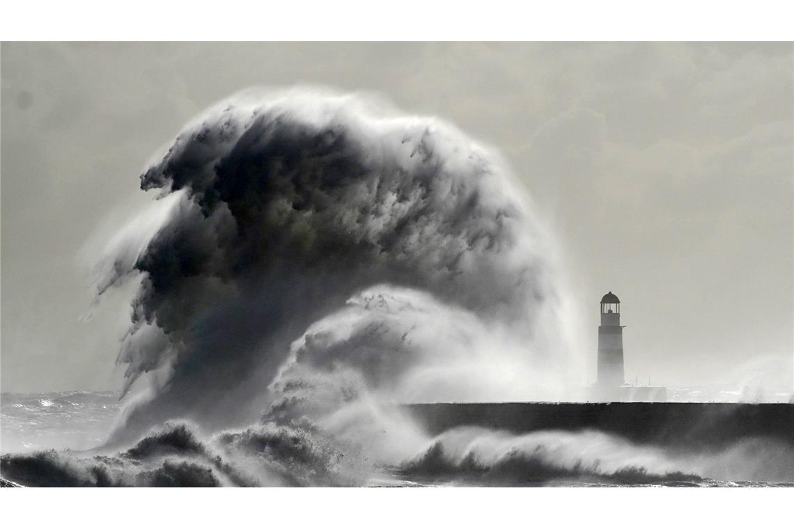 Große Wellen an der Mole vor dem Leuchtturm im Hafen von Seaham (England).