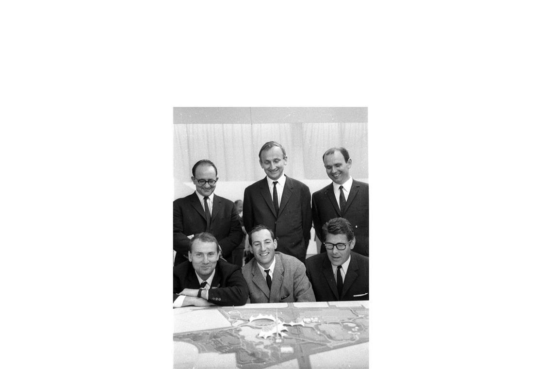 Günter Behnisch, Architekt des Olympiageländes 1972 in München,  ist oben Mitte stehend zu sehen. Weiter im Uhrzeigersinn: Winfried Büxel, Erhard Tränkner, Fritz Auer und Karlheinz Weber, genannt Carlo Weber, mit Jürgen Joedicke oben links.  Im Vordergrund ein Modell des Olympiageländes.