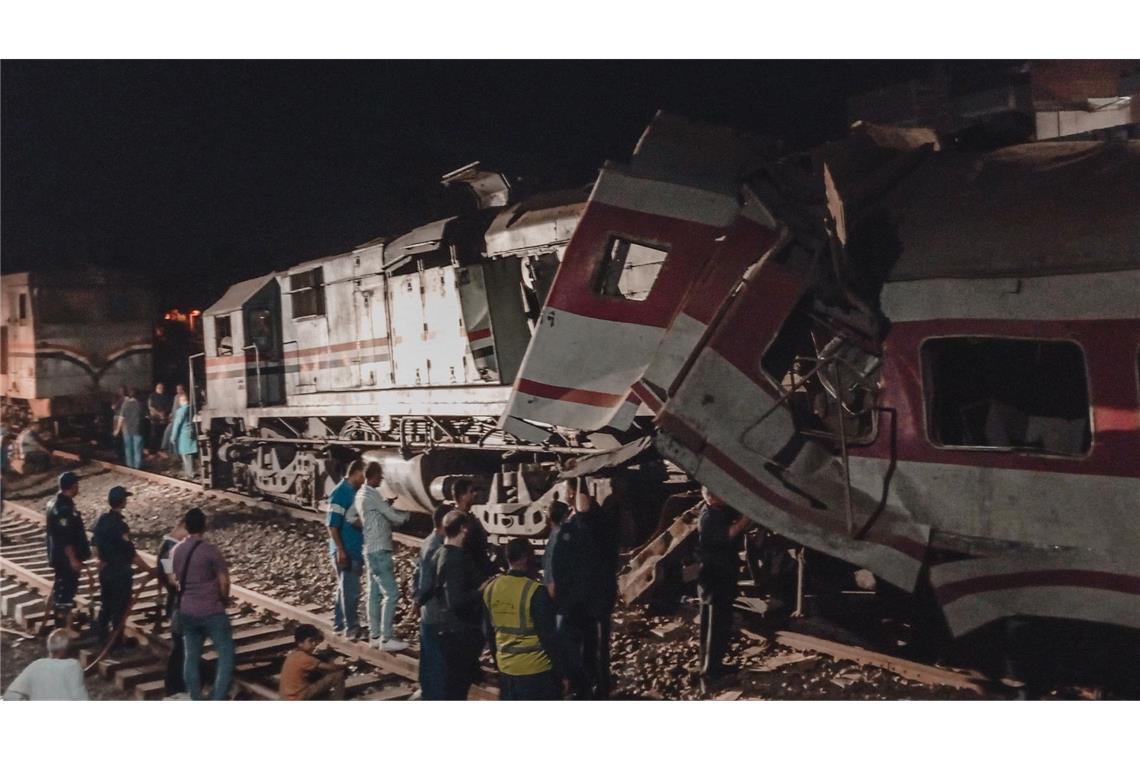 Helfer stehen neben einer entgleisten Lok nach einem Zugunglück in Ägypten.