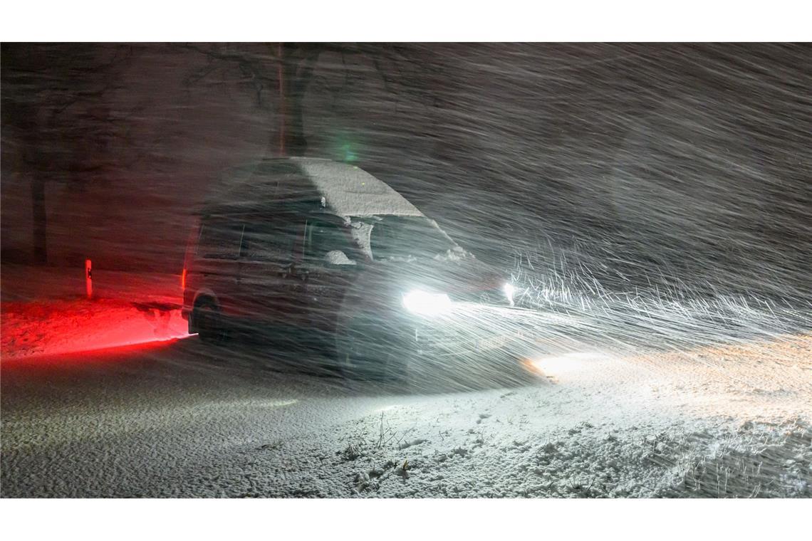 Im dichten Schneetreiben steht am Abend ein Kleintransporter am Straßenrand einer Allee im östlichen Brandenburg.