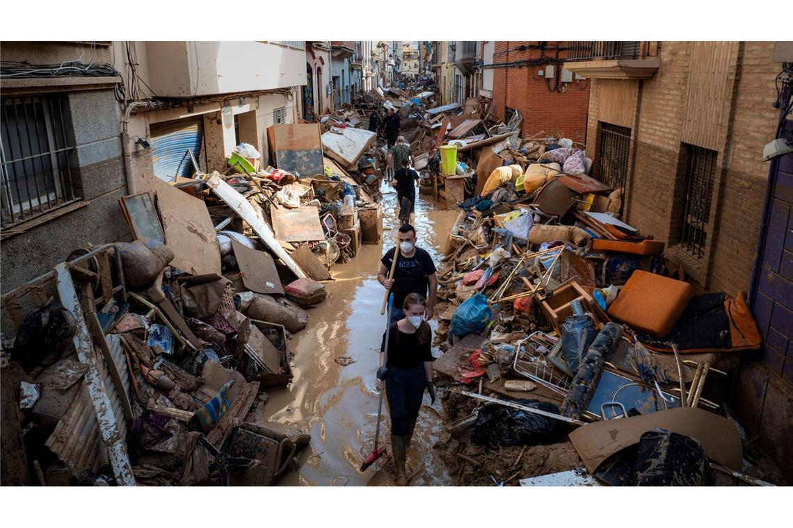 In Spanien bleibt die Situation nach den Überschwemmungen dramatisch. Hier gehen Menschen durch eine Straße voller Trümmer, Schlamm, beschädigter Möbeln und Müll in Valencia.