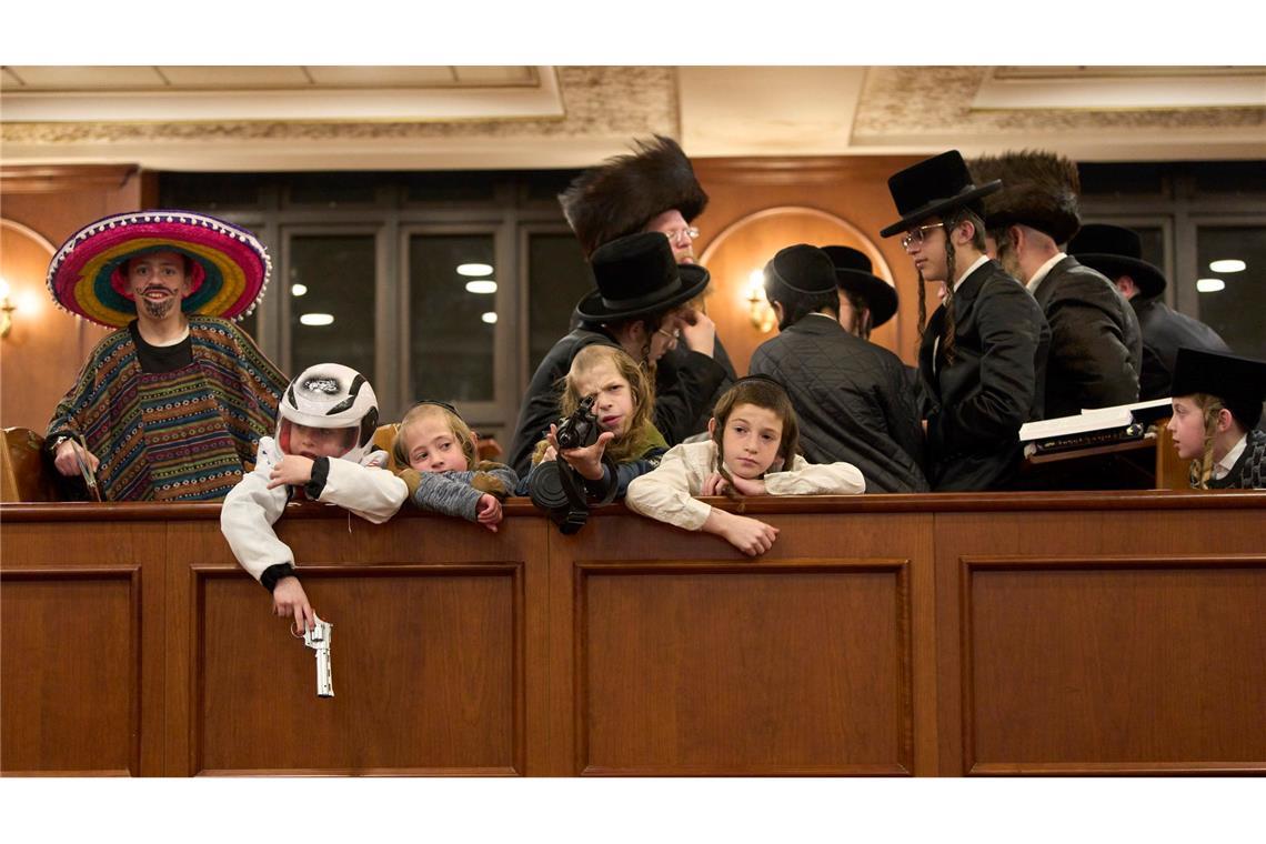 Jüdische ultraorthodoxe Männer und Kinder, von denen einige Kostüme tragen, halten sich in einer Synagoge in Jerusalem im Rahmen des Purimfestes auf.